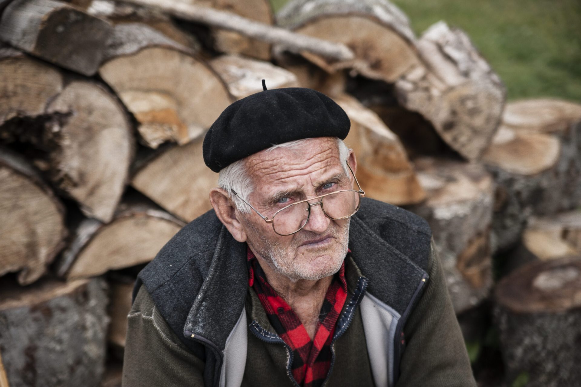 Lukomir, Bosnia and Herzegovina - July 14, 2013: Portrait of an old man sitting in front of a pile of fire wood in Lukomir. Lukomir, Bosnia and Herzegovina, July 14, 2013